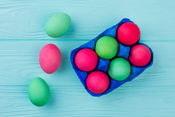 Hand dyed Easter eggs, top view. Colorful Easter eggs in blue tray on colorful wooden background. Easter holidays concept.