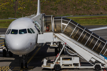 Obraz premium Plane with passenger boarding bridge connected to the door at the airport allowing passengers to board and disembark without going outside or being exposed to the elements