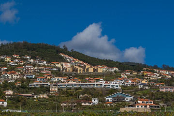 Fototapeta na wymiar Lanscape with colorful houses on the hills under the dramatic cloudy sky on a sunny day