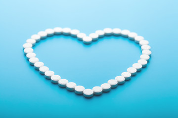 Obraz premium heart made up of pills on a blue background, health concept