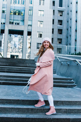 Cold and cute. Full length of beautiful young woman in pink coat looking away with smile while standing outdoors.