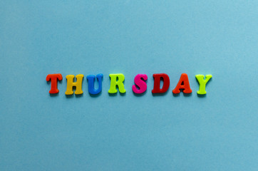 word "thursday" of colored plastic magnetic letter on blue paper background
