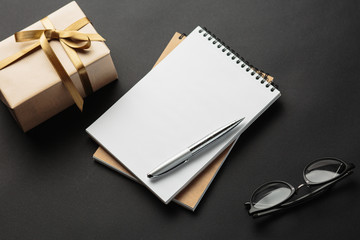 school notebook with gifts on black background, gift boxes with spiral notepad