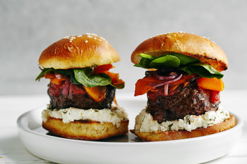Burgers with grilled beef patties, cream cheese and spinach on classical bun. White wooden background