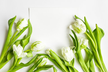 Letter and bouquet on white background. Invitation card, or love letter with white tulips. Top view, flat lay