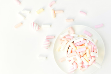 Colorful light marshmallows in a cup on white background. Top view, flat lay