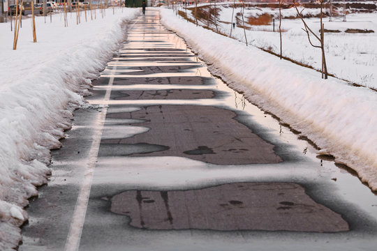 The sidewalk is springtime. snow and water.