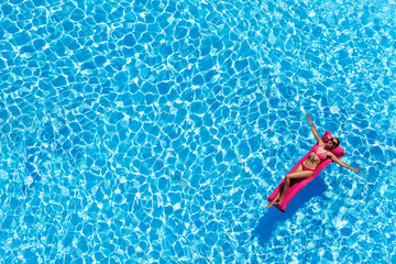 Slim young woman lying on air mattress in the pool