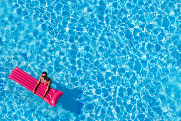 Woman swimming with inflatable mattress in pool