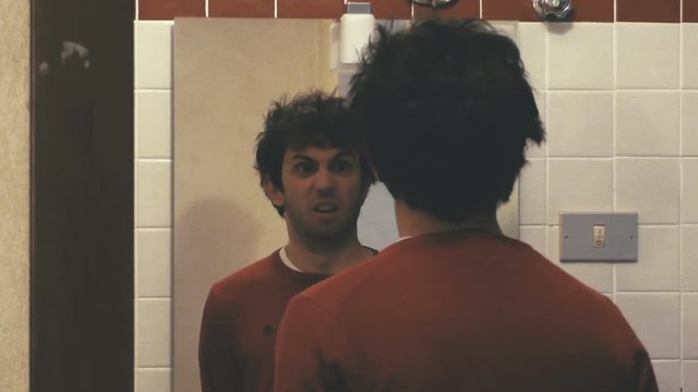 Weird boy making funny faces in the mirror.
