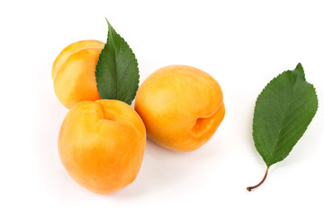 ripe juicy yellow apricots with leaves on a white table