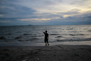 Naklejka premium a man looking for and walking on the beach at sunset