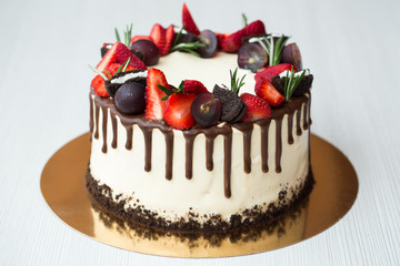 Cake with chocolate stains, strawberries, grapes, rosemary and Oreo