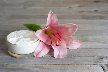 Moisturizer and lily flower on weathered wooden