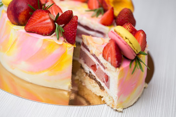 Cake yellow and pink splotches, strawberries, peaches, macaroons, rosemary. The cut of the cake. A piece of cake