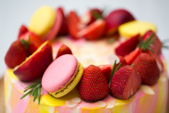 Cake yellow and pink splotches, strawberries, peaches, macaroons, rosemary