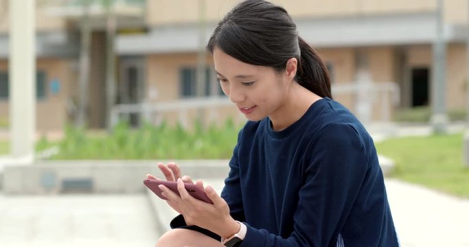 Woman playing game on smart phone at outdoor park