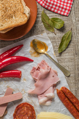 Ingredients for preparing the traditional portuguese snack food. Francesinha sandwich of bread, cheese, pork, ham, sausages, with tomato, beer, sauce and french fries.