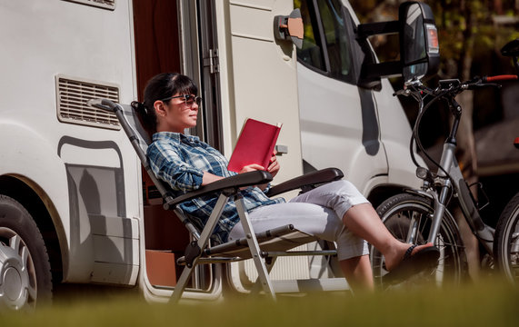 Woman relaxes and reads a book near the camping .