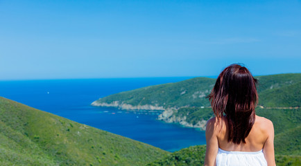 Young girl looking at a sea coast line in Greece in summertime