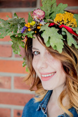 Naklejka premium young redhead woman with oak leaves wreath on brick wall background