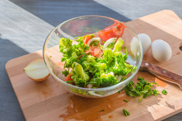 Raw broccoli and vegetables in a glass bowl