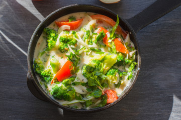Mixed raw eggs, broccoli and tomatoes and vegetables in a frying pan - cooking omelette tomatoes