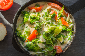 Mixed raw eggs, broccoli and tomatoes and vegetables in a frying pan - cooking omelette tomatoes