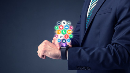 Businessman wearing smartwatch with colored application symbols on it.