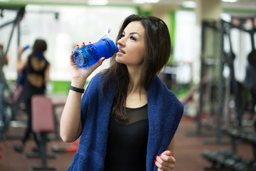 Attractive sport girl smiling and drinking water while standing in fitness class
