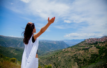 Young girl in white clothes standing on rock in Greece with view at mountains