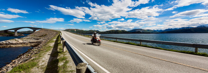 Fototapeta premium Biker rides a road with Atlantic Ocean Road in Norway.