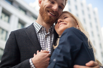 Happy attractive young couple to share a good joke, laughing loudly, embracing each other outdoors in urban environment
