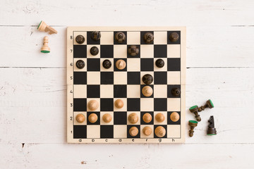 Top view on wooden chess board with figures during the game on white wooden table background - 197871526