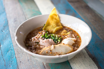 Spicy Noodles Tom Yum with pork on wooden table