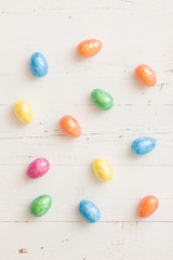 Top view on pattern of colorful Easter decoration eggs on white wooden table background