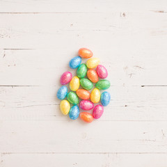 Top view on colorful Easter decoration eggs in a shape of egg on white wooden table background