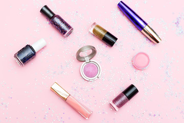 Obraz premium Decorative cosmetics on a pink background with sparkles. Flat lay