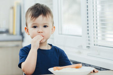baby eating sausage in the kitchen is very charming and emotional