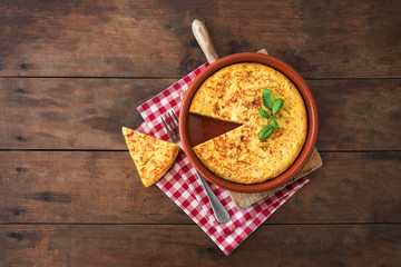 Spanish potato omelet called tortilla de patatas on a rustic wooden texture with a place for text.