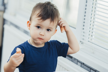 baby eating sausage in the kitchen is very charming and emotional