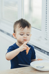 baby eating sausage in the kitchen is very charming and emotional
