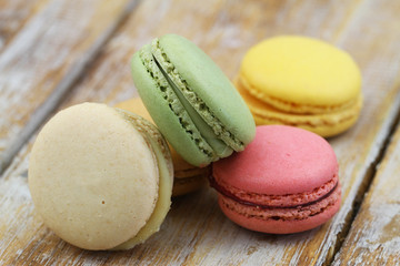 Close up of pistachio, raspberry, lemon and vanilla macaroons on wooden surface
