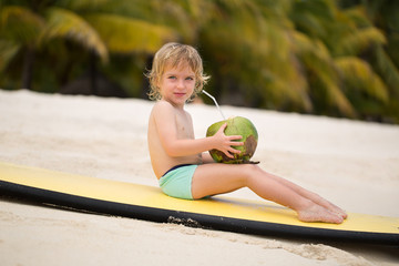 Happy funny little preschool kid boy drinking coconut juice on ocean beach.