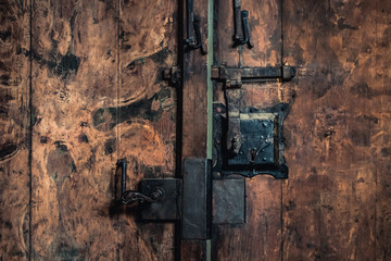 Close-up photo of an old rusty metal lock mechanism on a wooden door.