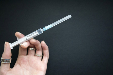 Woman's hand holding a syringe with needle