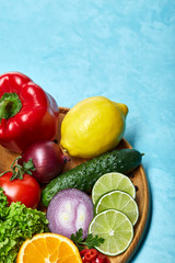 Still life of fresh organic vegetables on wooden plate over blue background, selective focus, close-up