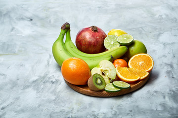 Ripe fresh fruits in a wooden plate on a light background, selective focus, close-up, top view