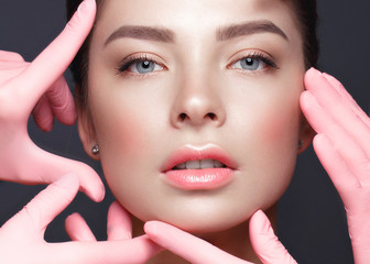 Beautiful young girl with natural nude make-up with cosmetic tools in hands. Beauty face. Photo taken in studio