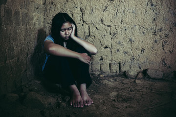 Sad little girl sitting against the wall in despair.